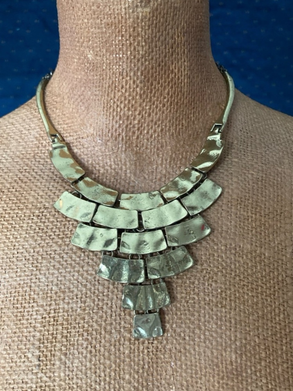 The necklace features a rigid collar band that transitions into multiple danglin
